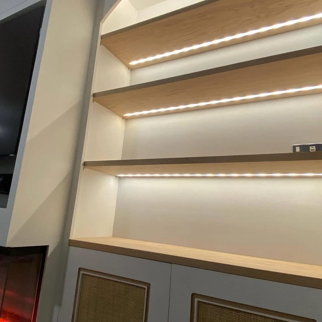 Close-up of LED strip lighting set into floating oak shelves
